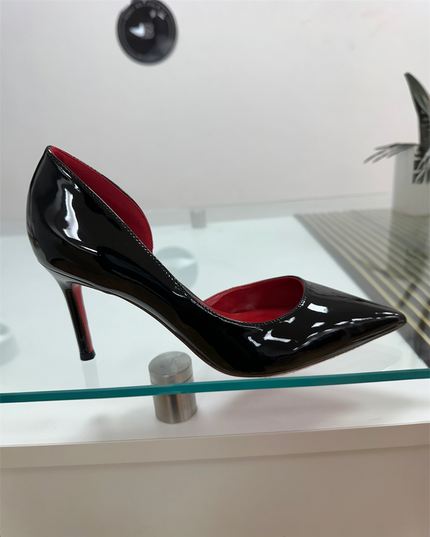 Black patent leather high-heeled shoe with a red sole.